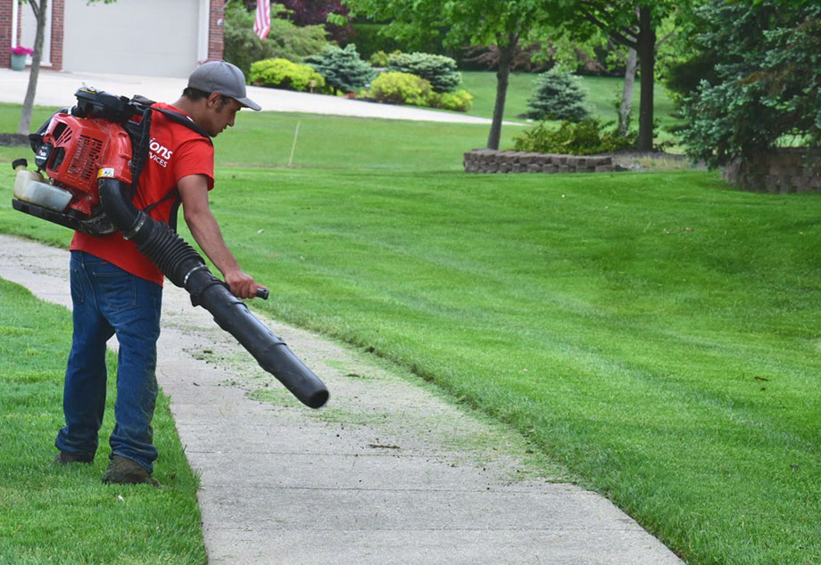 Transitions team member cleaning up freshly cut grass clippings