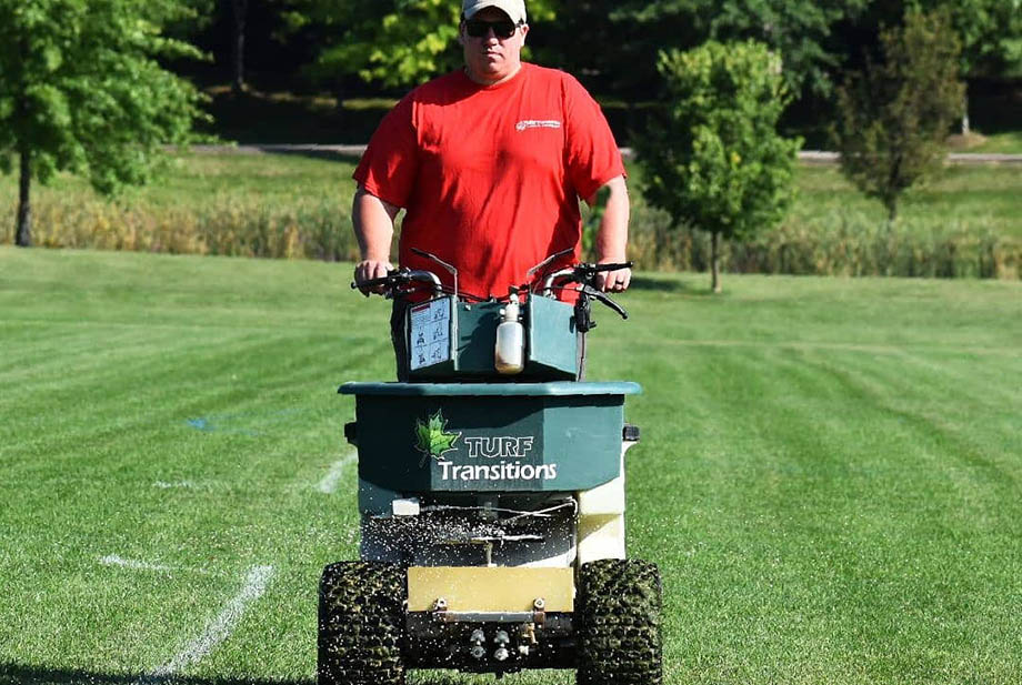 Transitions team member fertilizing lawn.